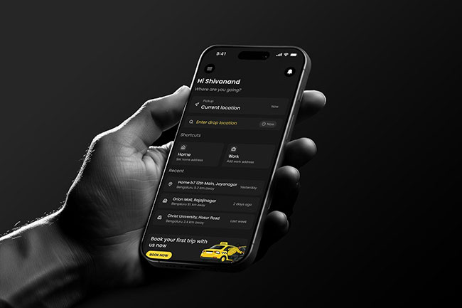 A hand in a grayscale photo holds a smartphone displaying a dark mode interface for a ride-hailing app, featuring recent locations in Bengaluru and a booking option
